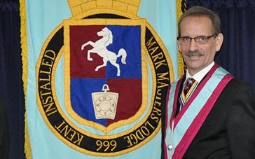 Ian Gallehawk - Incredible Member Profile 4 An image of Ian Gallehawk standing next to the banner for the Province of Kent Mark Master Masons