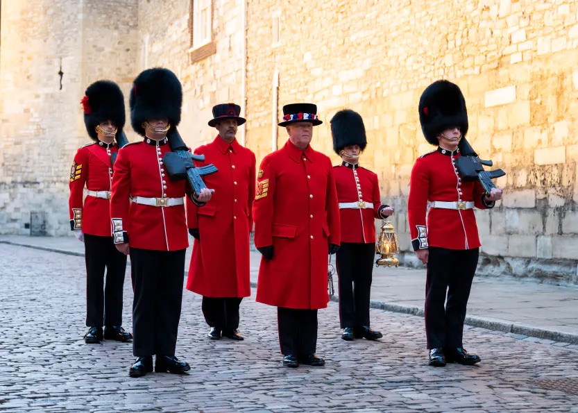 Free Ceremony of the Keys - 04.12.2023 1 Ceremony of the keys - A picture of the Chief Yeoman Warder carrying the keys flanked by 4 armed guards wearing red tunics and bearskins with another yeoman Warder to his rear